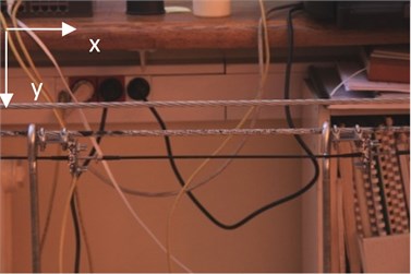 Measurement of a cable deflection: a) the laboratory stand; b) the field of view of the Canon EOS 5D MII camera (with 42 mm focal length) used to the compute displacement field of the cable under the load; c) the field of view of the Canon 450D camera (with 96 mm focal length) used to compute the relative displacement between two Bragg sensors; d) image of the cable divided into a set of intensity patterns