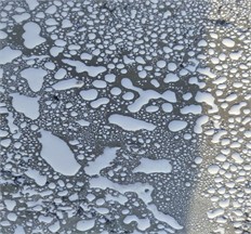 Verification of film-forming materials: a) type of film-forming material with expired shelf life, sprayed on the surface of freshly laid cement concrete; b) separation of film-forming material and formation of particles larger than 1 mm. Photograph taken by Tukhtayev Matchon Bekjonovich in the laboratory and on field test sections of newly constructed cement concrete pavement, Tashkent, Uzbekistan