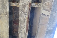 Concrete beams of the bridge span structure: a), b) defects in concrete bridge beams  in the form of exposure, active corrosion, and broken wire strands; c) view of the outer beams  of the bridge, reinforced with MMA-adhered external reinforcement
